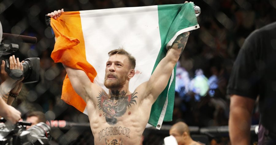 McGregor+holds+up+the+Irish+flag+to+represent+his+country+after+a+victorious+match.