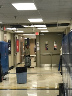 Janitorial staff cleans up water from the pipe breakage right outside of the school store in A-wing. 