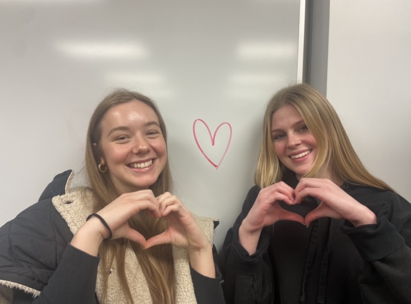 Gal Pals, Anna Engels and Baily Randall pose by a heart for Galentines day.