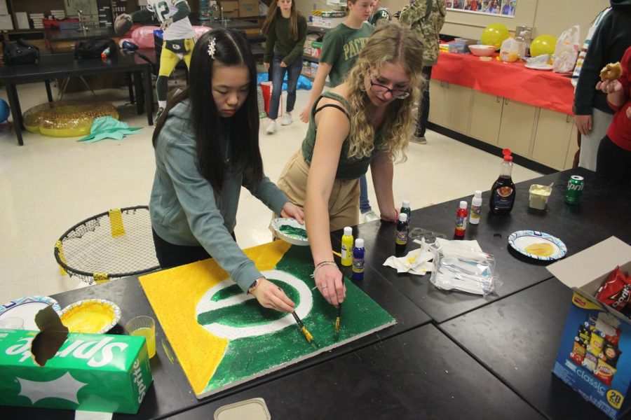 Hannah Basel and Vanessa Ung paint the ceiling tile with the Packers logo.