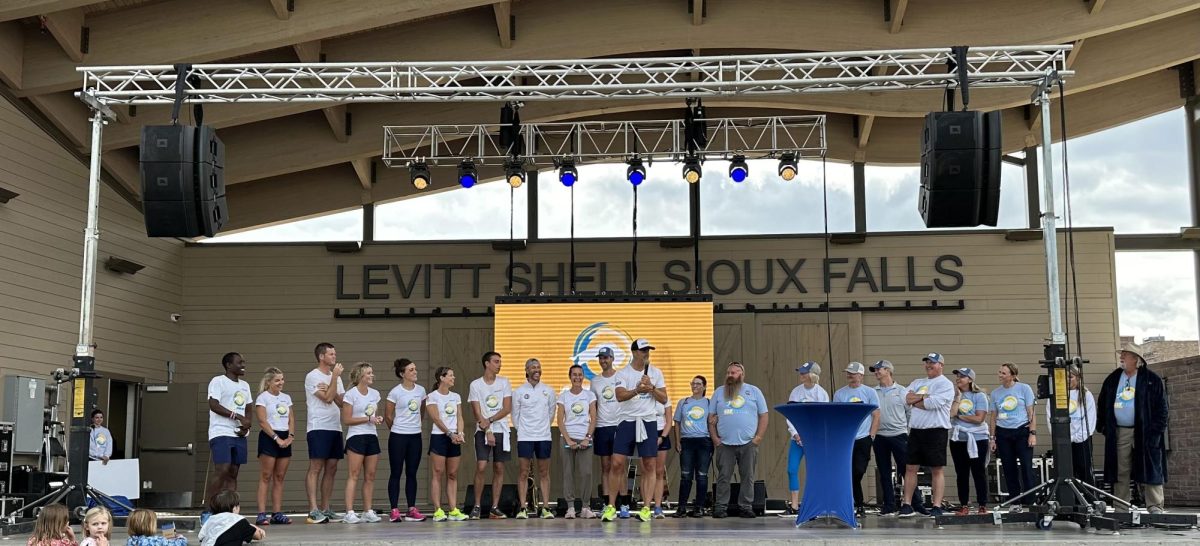 The 12 runners and the volunteers stand up on stage at the Levitt Shell as Sioux Falls Mayor Paul TenHaken talks about The 437 Project. 
