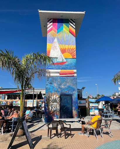 A mural at Fort Myers beach that says “Shine on FMB,” showing the sunsets and boats in the water. 