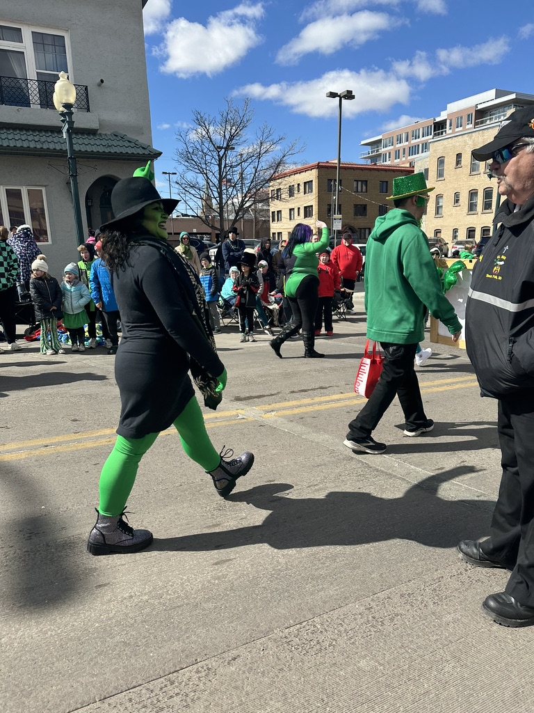 Members of Supercon march down Phillips Avenue in festive costumes, greeting all viewers with a smile and wave. 