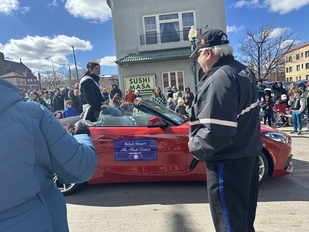 Miss South Dakota, Miranda O’Bryan, proudly rides through the parade, greeting viewers with a smile and wave. 