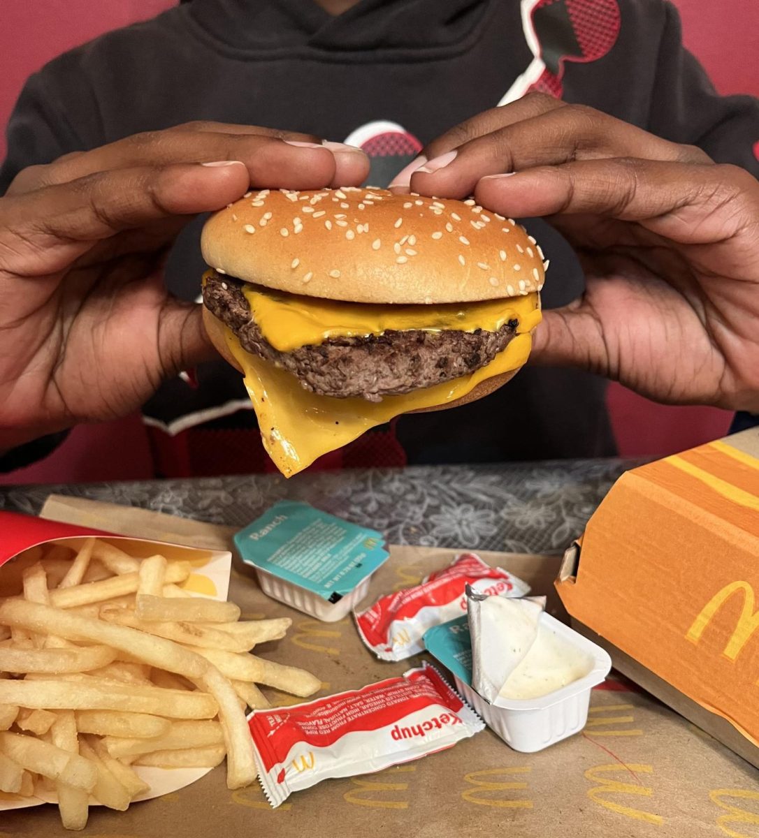 A hungry customer holds a quarter pounder, paired with crispy fries and dipping sauces. 