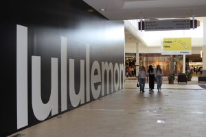 A group of shoppers walking next to the Lululemon construction wall.