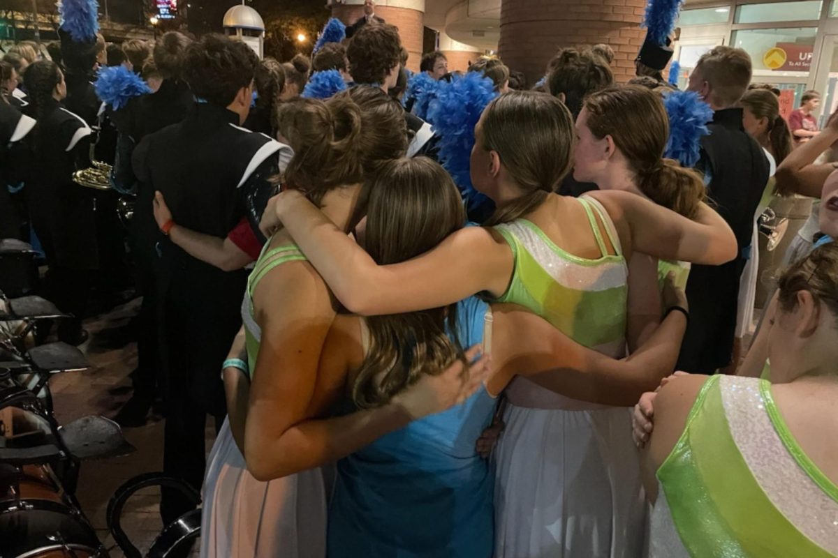 LHS freshmen colorguard members huddle together after their preliminary performance of “Take a Moment.” (Photo used with permission by Gaea Noordsy)